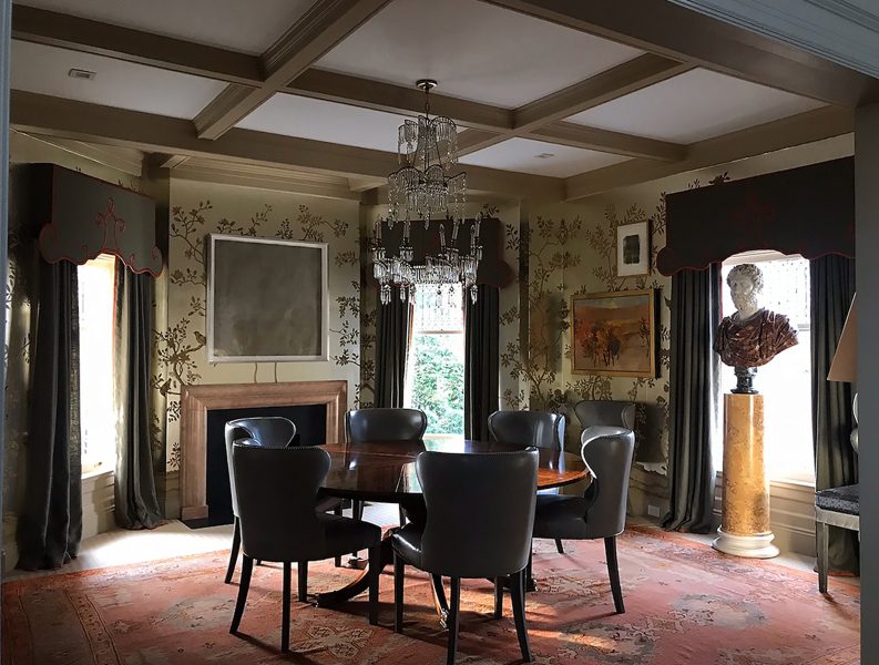 Roundtable gathering area with antique  bust, chandelier and wallpaper. 