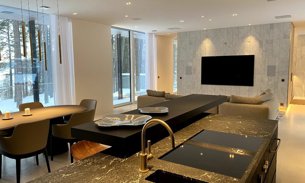 Clean Scandinavian design of interior woodland home. Black marble sink countertops and TV mounted on stonework.