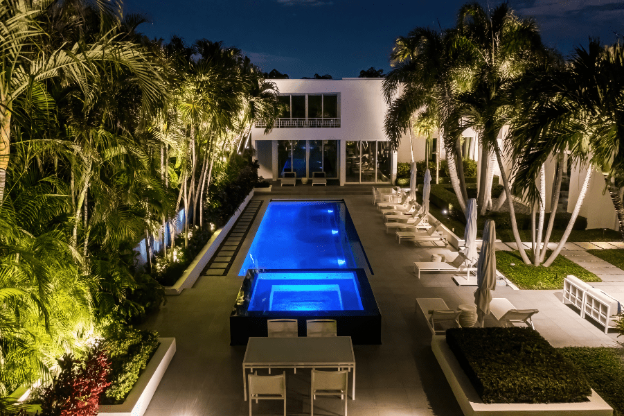 Overview shot of pool and jacuzzi in Florida, ETC, landscape lighting at night, tropical oasis setting